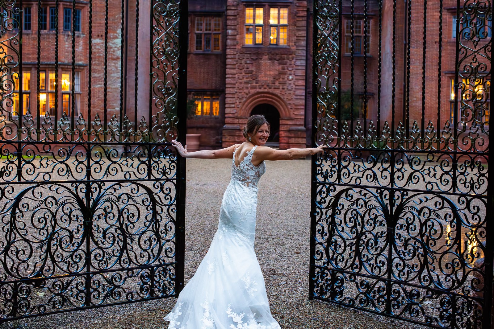Bride opening a large gate during wedding photography.