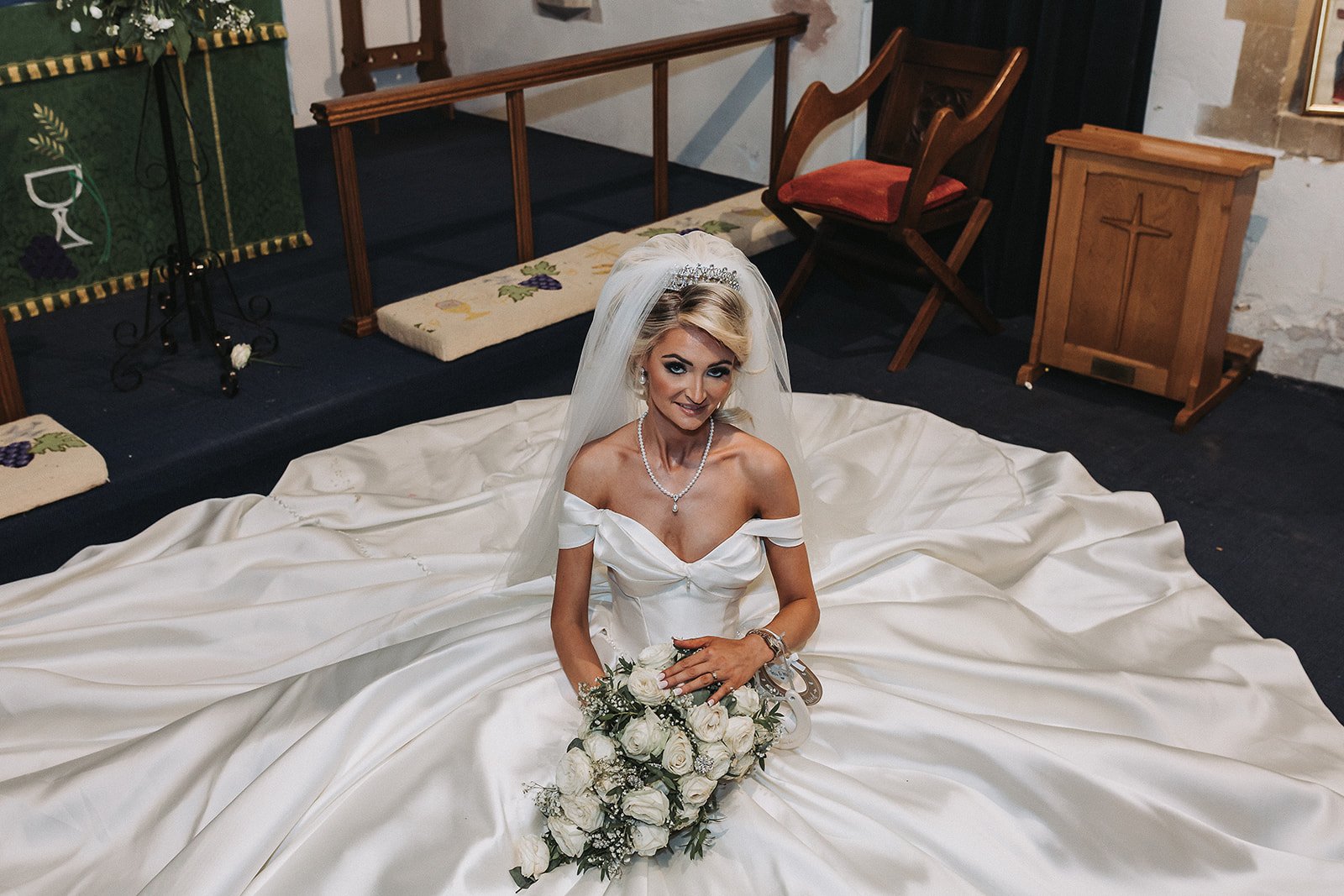 Bride sitting on the floor holding her flowers bouquet during wedding photography.