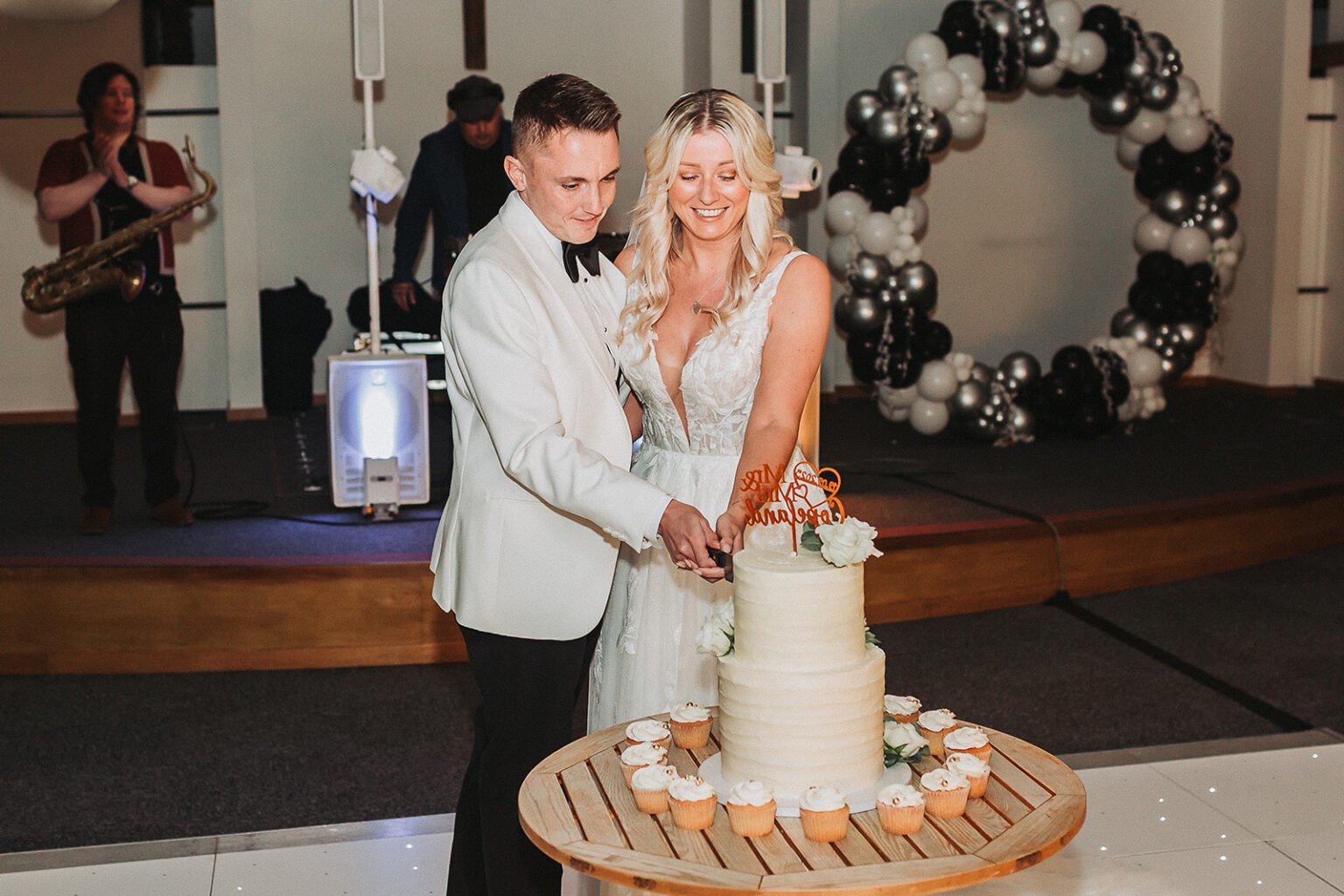 Bride and groom are cutting the wedding cake in the party in Alton Maltings.