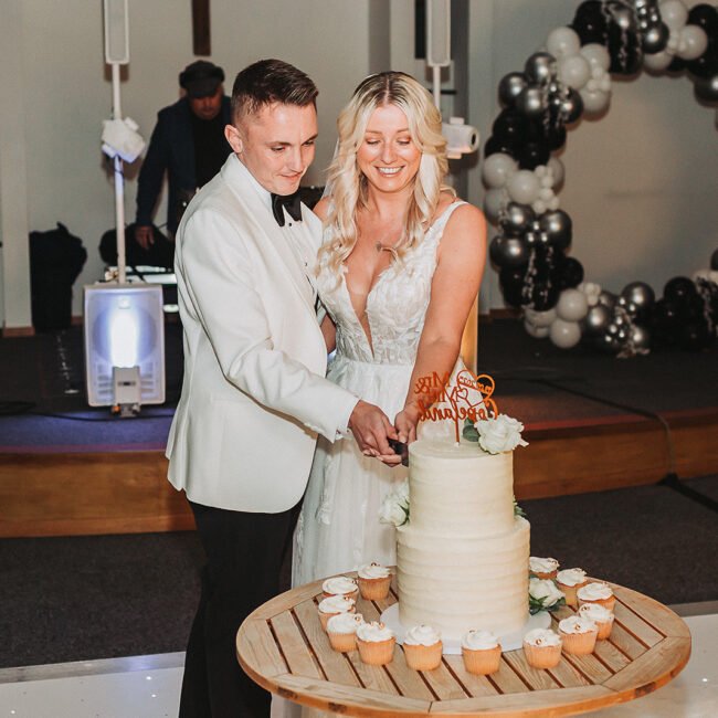 Bride and groom are cutting the wedding cake in the party in Alton Maltings.