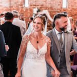 Bride and groom are smiling to their guests.