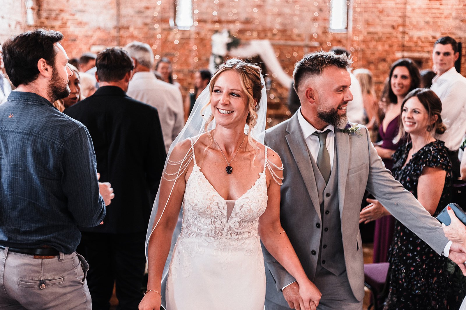 Bride and groom are smiling to their guests.